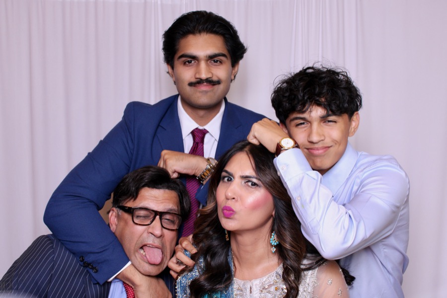 A group of friends in front of a photobooth posing for the photo.