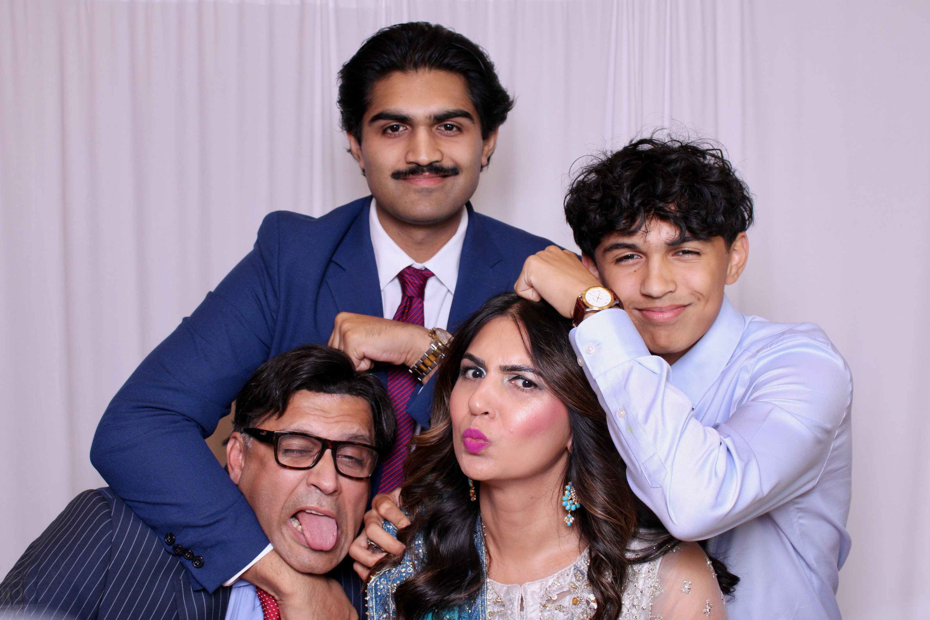 A group of friends in front of a photobooth posing for the photo.