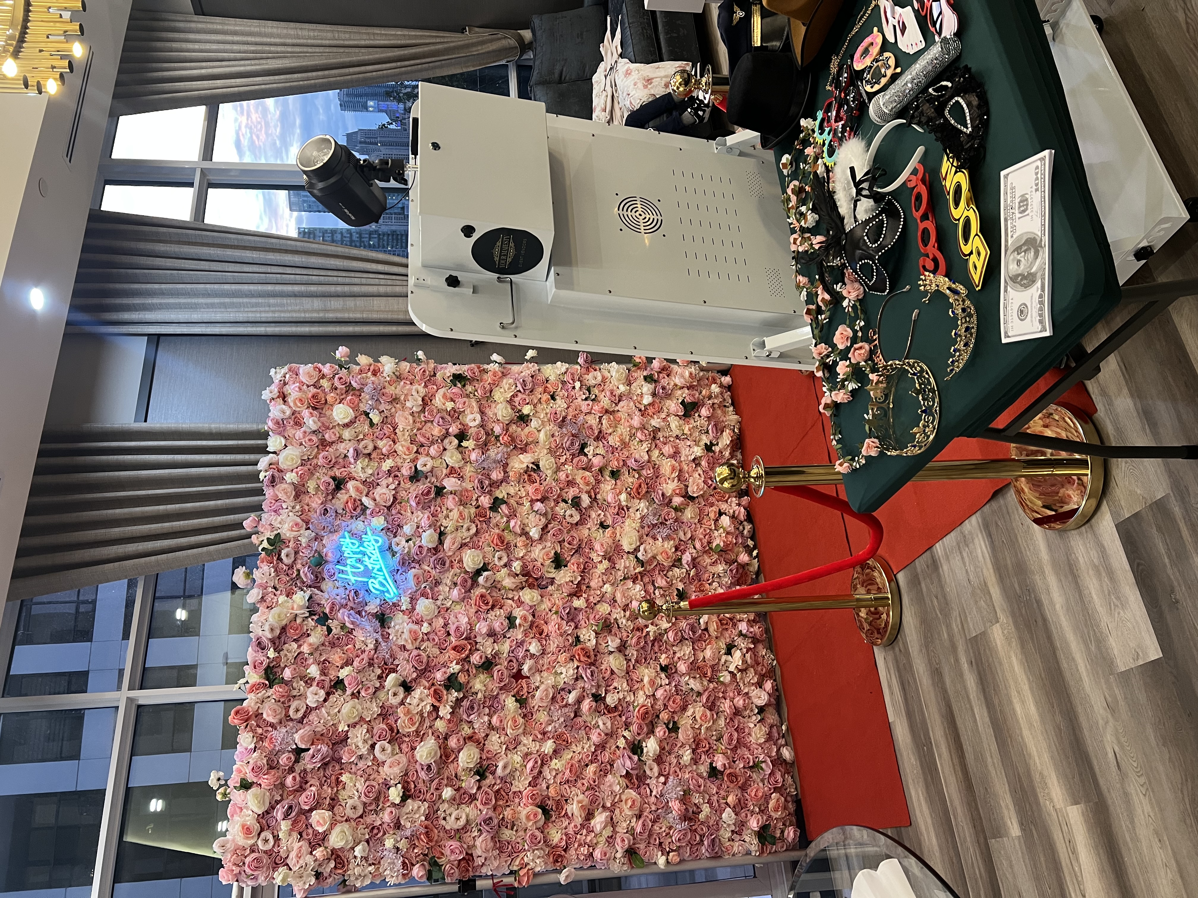 A photobooth setup with a flower wall and prop table.