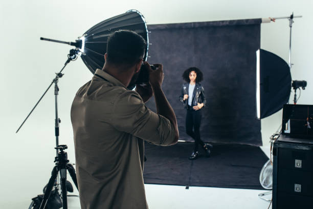 A person posing for a photographer in a studio setting.